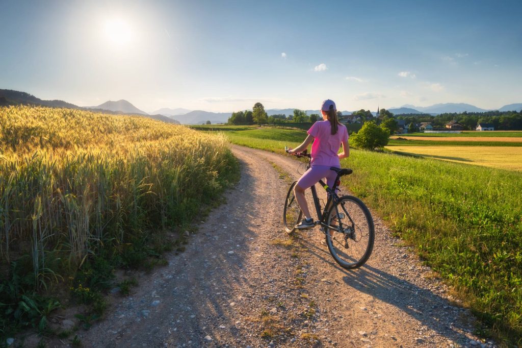cyklistka na poľnej ceste s vyhľadom na hory